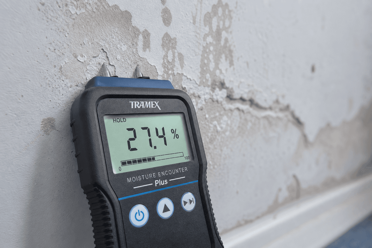 Professional moisture meter reading 27.4% on water-damaged drywall — precise measurement is the foundation of correct drying